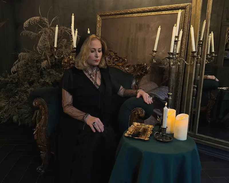 Alice seated in an armchair by a table of candles