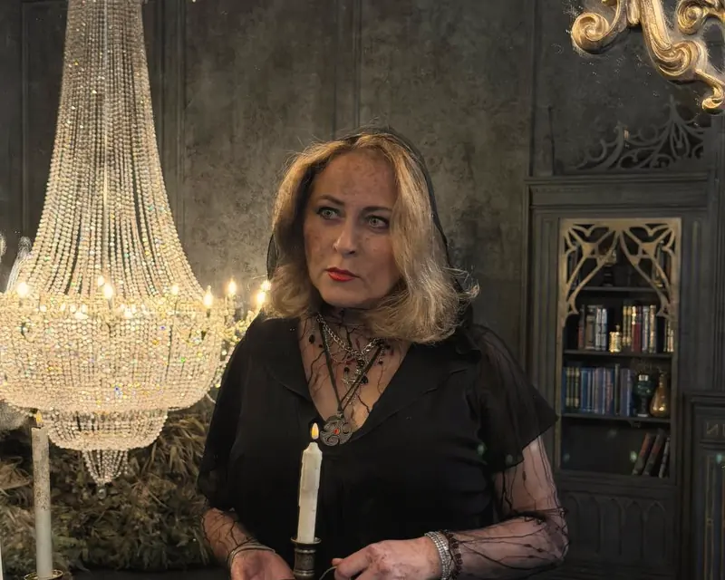 Alice holding a candle beside a crystal chandelier