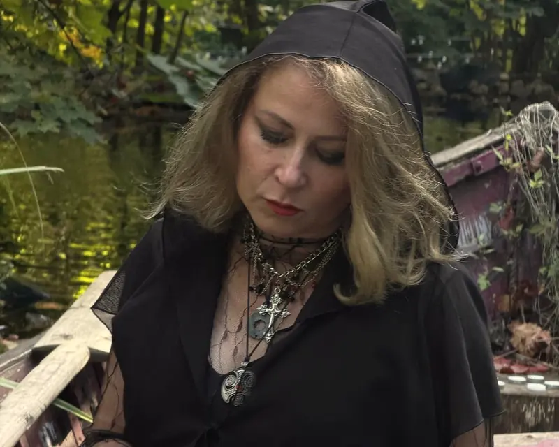 Alice in a hood holding a black deck of cards