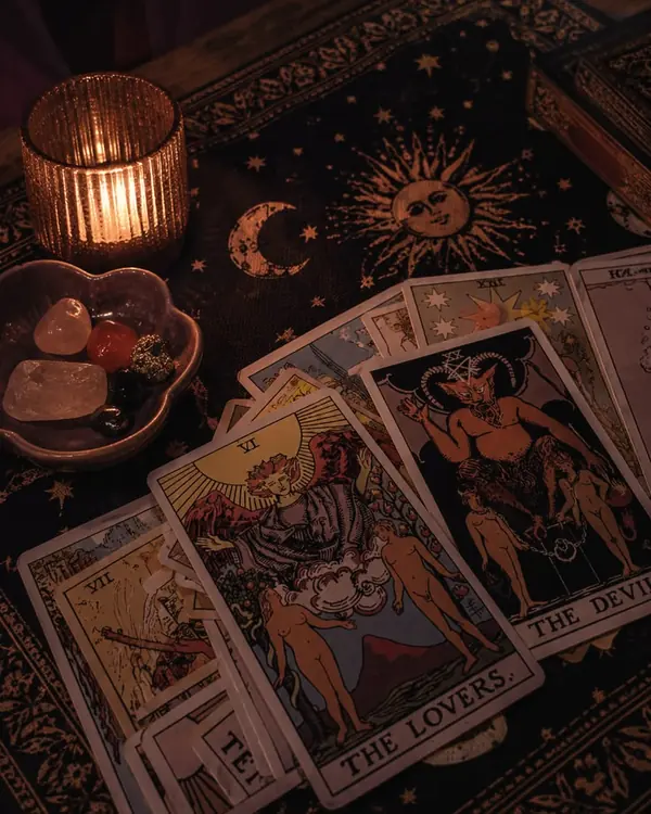 Tarot cards laid out on dark cloth beside a candle and stones